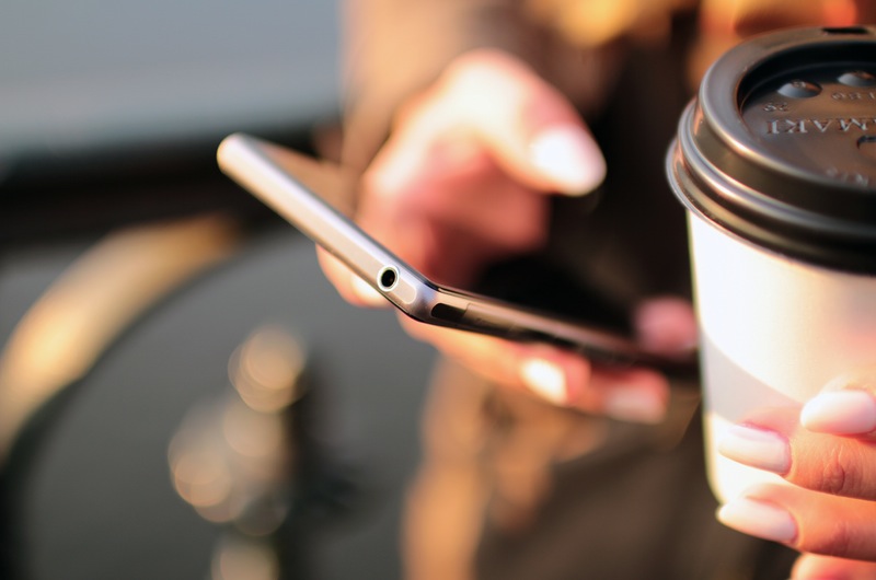 Hands holding a Smartphone and Coffee