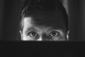 BW photo of man looking over over laptop