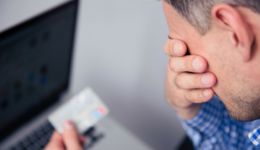 Man upset holding a credit card by computer