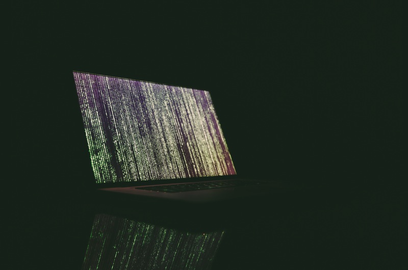 Mac in the dark with binary on screen