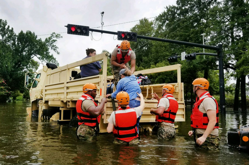 Texas National Guardsmen assist residents affected by flooding caused by Hurricane Harvey onto a military vehicle
