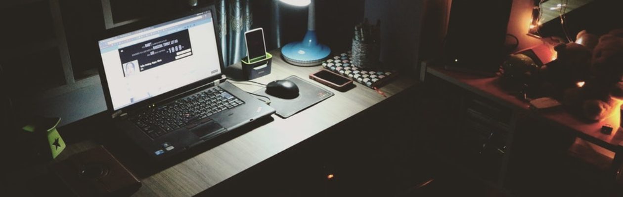 Laptop in dark room on a desk with a blue lap shinning