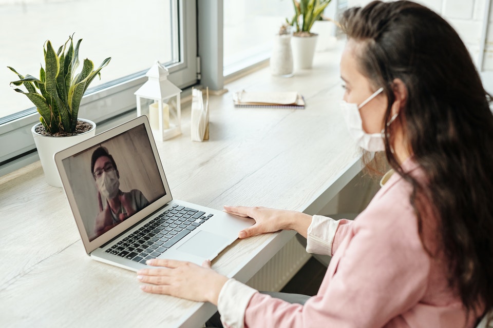 woman having a video call on her computer both people wearing a mask
