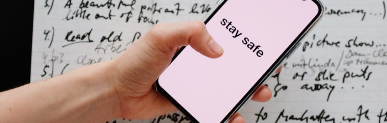 Person holding phone with text "Stay Safe" on screen