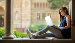 Student sitting on college campus with laptop