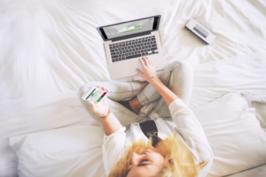 Woman sitting on bed using phone to authenticate to use computer