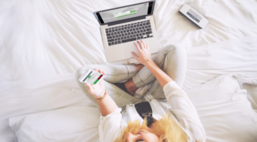 Woman sitting on bed using phone to authenticate to use computer