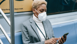 Woman on subway using mobile phone and wearing a mask