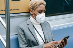 Woman on subway using mobile phone and wearing a mask