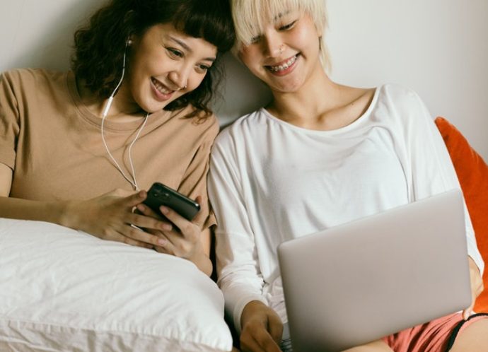 Two cheerful women using tech
