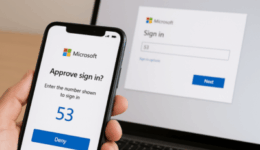 Person holding a cellphone with MS Authenticator App on screen with a laptop showing the authentication